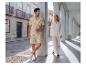 Homme en chemise et short beiges à motif feuilles, femme en chemise et pantalon blancs.