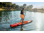 Homme faisant du paddleboard sur un lac, entouré d'arbres et de montagnes.