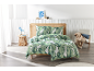 Chambre avec un lit à tête de lit en rotin et une parure de lit à motif de feuilles vertes.