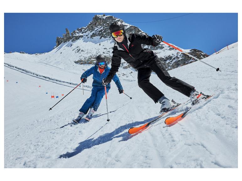 Deux skieurs en tenue de ski noire et bleue sur une pente de montagne enneigée.