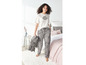 Une femme portant un t-shirt blanc avec un imprimé de lèvres et un pantalon de pyjama rayé.