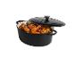 Cocotte ovale en fonte émaillée noire avec couvercle, remplie de poulet rôti et de légumes.