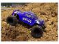 Un monster truck Whelon bleu gravit une colline de terre.