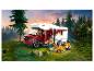 Camping-car Lego avec figurines campant près d'un feu de camp en forêt.