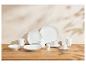 Service de table en porcelaine blanche avec assiettes, bols, tasses et pièces de service sur une table en bois.
