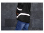 Une veste noire avec des bandes réfléchissantes et un jean bleu.