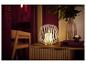 Bougie LED LIVARNO® dans un panier métallique sur une commode en bois avec vase et livres.