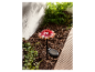Lampe solaire en forme de champignon rouge à pois blancs dans un jardin.
