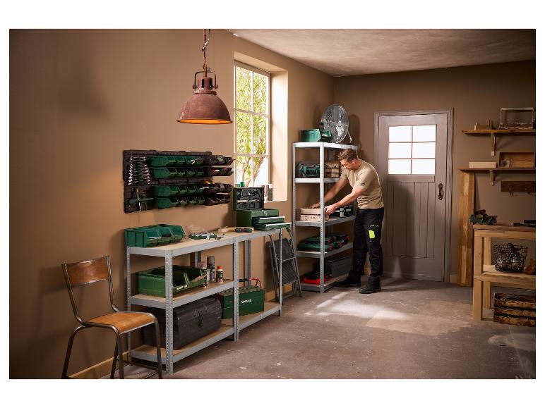Homme dans un atelier organisant des outils sur des étagères et un établi.