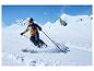 Un skieur avec un pantalon bleu et une veste marron descend une pente à ski.