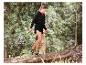 Femme en short et sweat à capuche noirs marchant sur un tronc d'arbre en forêt.