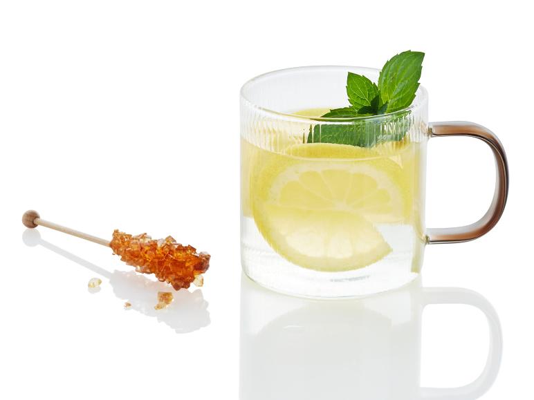 Un verre de thé au citron et à la menthe et une baguette de sucre cristallisé.