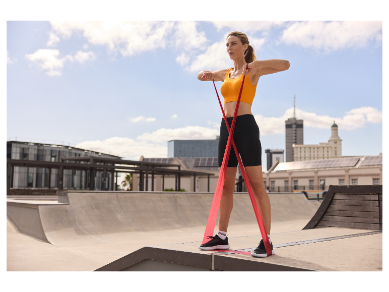 Femme faisant des exercices avec un élastique en extérieur.