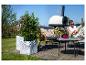 Pots de plantes avec des plantes sur une terrasse en bois, avec une femme qui se détend en arrière-plan.