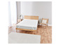 Un protège-matelas blanc sur un cadre de lit en bois.