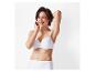 Une femme sourit en portant un soutien-gorge blanc et des sous-vêtements taille haute.