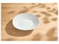 Bol blanc vide sur une table en bois clair avec des ombres de feuilles.