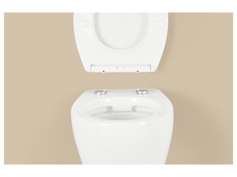 Abattant de toilettes blanc relevé, avec charnières métalliques visibles sur la cuvette.
