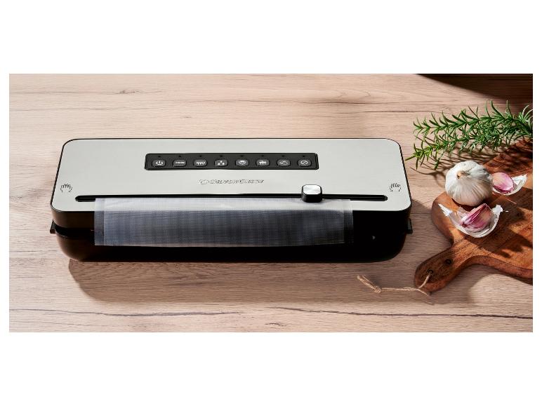 Machine sous vide SilverCrest sur une table en bois avec ail et romarin.