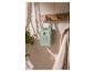 Radio portable verte suspendue à un porte-manteau en bois dans une salle de bain avec une plante et une serviette.