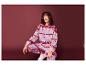Une femme porte un pull de Noël rose et un pantalon assorti.