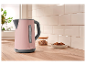 Une bouilloire rose SilverCrest sur un comptoir en bois.