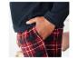 Un homme porte un sweat en polaire bleu marine avec un pantalon de pyjama à carreaux rouge et noir.