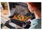 Une personne sort une plaque de cuisson avec du poulet rôti et des légumes du four.