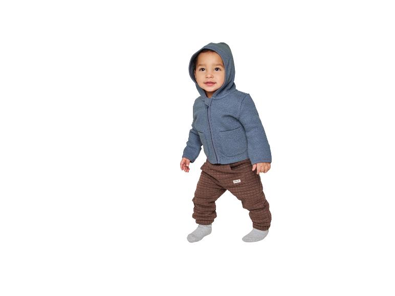 Tout-petit en sweat à capuche bleu et pantalon matelassé marron.
