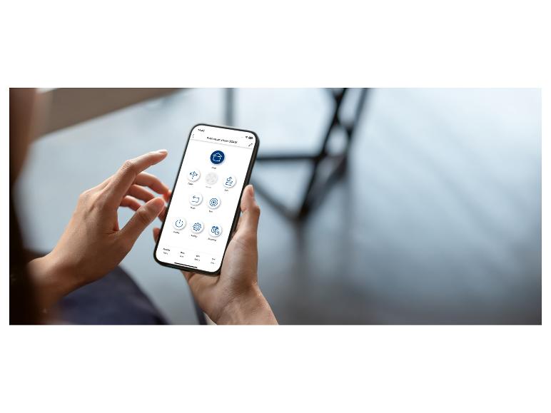 Une personne tenant un smartphone affichant une application d'aspirateur robot avec diverses options de contrôle.