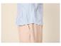 Chemise rayée bleue et blanche avec un pantalon beige.