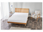Un matelas blanc sur un cadre de lit en bois dans une chambre.