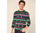 Un homme souriant portant un pull de Noël coloré avec des bonshommes de pain d'épice et des motifs HO HO HO.