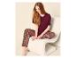 Femme assise sur une chaise, portant un t-shirt bordeaux et un pantalon de pyjama à motifs.