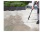 Nettoyeur haute pression nettoyant une terrasse en dalles de pierre avec jardinières.