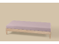Cadre de lit en bois clair avec matelas violet clair sur fond beige.