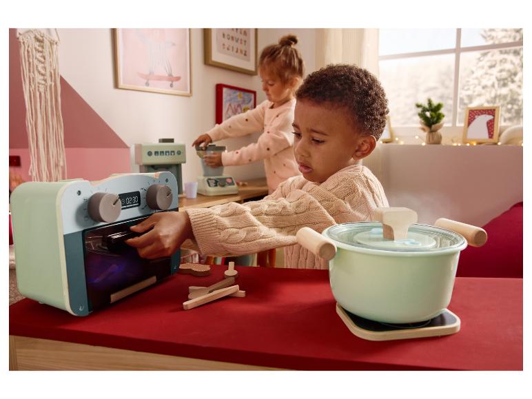 Deux enfants jouent avec des appareils de cuisine jouets, dont un four et une casserole.