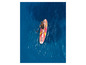 Une femme pagaye sur un paddleboard gonflable rose et jaune en mer.