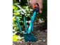 Un rateau à main bleu est utilisé pour désherber dans le jardin.