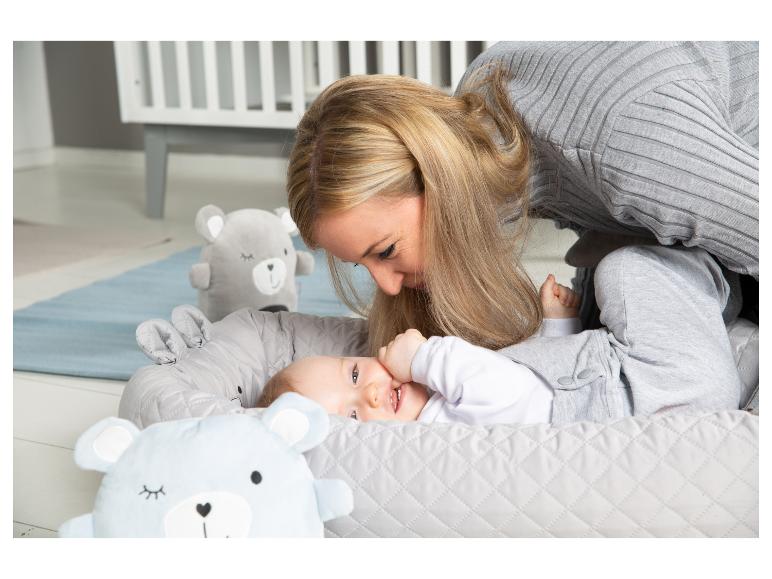 Mère et bébé dans un nid douillet gris avec des ours en peluche dans une chambre d'enfant.