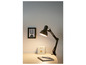 Une lampe de bureau noire éclaire un bureau avec un carnet et une boîte.