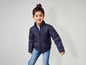 Une fille porte une veste d'hiver bleue et un jean.