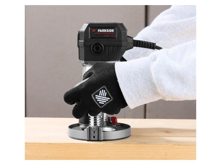 Personne gantée utilisant une défonceuse Parkside Performance sur une planche en bois