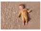 Bébé dans une combinaison jaune avec un imprimé ours, allongé sur une couverture beige.