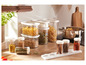 Des pâtes, du muesli et des épices dans des bocaux en verre sur un comptoir en bois.