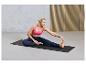 Une femme en tenue de sport fait du yoga sur un tapis noir.