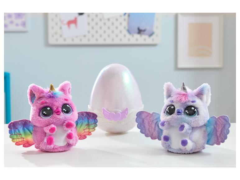 Deux jouets licornes en peluche colorés avec des ailes et un grand œuf irisé sur une surface blanche.