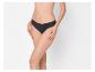 Une femme porte une culotte noire, les mains sur les cuisses, sur fond blanc.