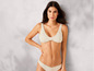 Une femme porte un bikini beige, haut et bas.