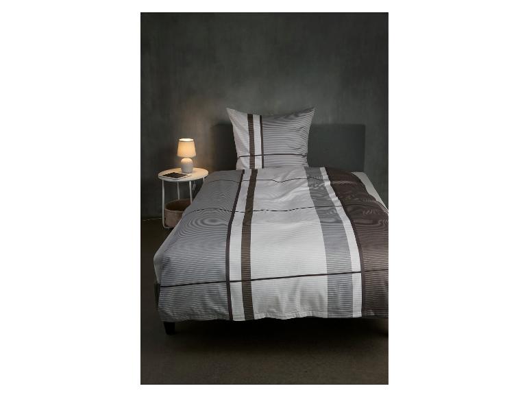 Chambre à coucher avec parure de lit rayée, table de chevet et lampe.
